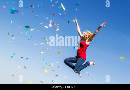 Junge Frau mit Konfetti springen Stockfoto