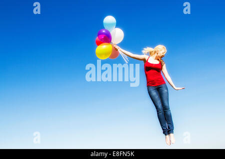 Portrait von fliegenden Frau mit Haufen Luftballons Stockfoto