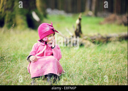 Kleines Mädchen (2-3) sitzen im Wald Stockfoto