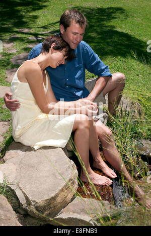 Paar sitzt mit Füßen im stream Stockfoto