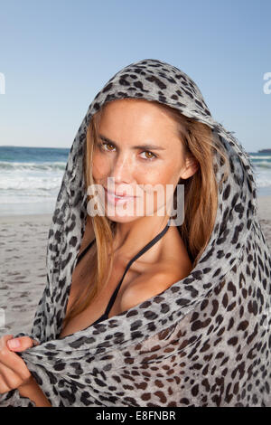 Porträt der lächelnde Frau am Strand eingewickelt in Leopard print Schal, Cape Town, Südafrika Stockfoto