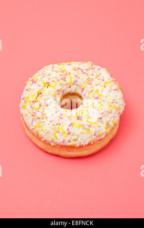 Iced Donut mit Streuseln auf einem rosa Hintergrund Stockfoto