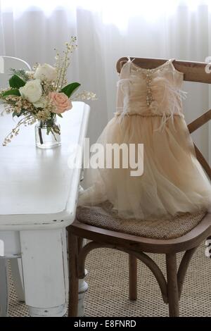 Des Mädchens Ballett Kleid auf Stuhl neben Vase mit Rosen Stockfoto