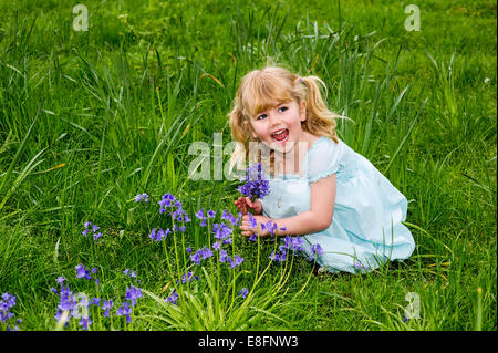 UK, Warwickshire, Rugby, glückliches Mädchen (4-5) Abholung Glockenblumen auf Wiese Stockfoto