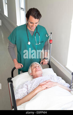 Arzt bewegliche Patienten im Bett entlang Krankenhausflur Stockfoto