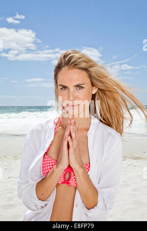 Junge Frau am Strand mit Händen in Gebetsstellung, Kapstadt, Westkap, Südafrika Stockfoto