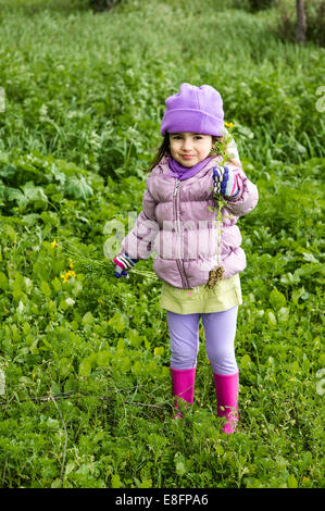 Porträt eines kleinen Mädchens (4-5), das Wildblumen im Freien hält Stockfoto