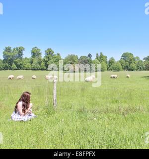 Teenager-Mädchen sitzen auf einer Wiese Blumen pflücken Stockfoto