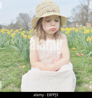 Mädchen sitzen in einem Feld schmollen Stockfoto