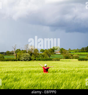 Rückansicht der Junge stand im Feld mit ausgestreckten Armen Stockfoto