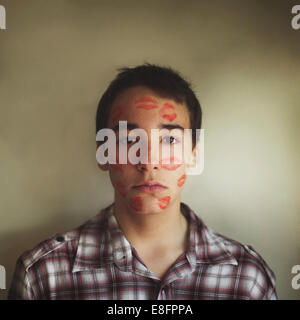 Porträt eines Teenage Jungen mit Lippenstift Küsse bedeckt sein Gesicht Stockfoto