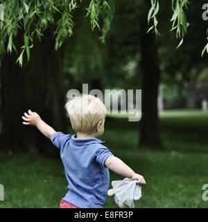 Rückansicht des kleinen Jungen laufen im Park mit ausgestreckten Armen Stockfoto