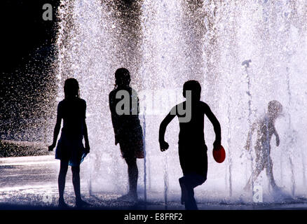 Silhouetten von Kindern beim Spielen im Wasser-Brunnen Stockfoto