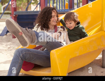 Mutter und Sohn auf einer Folie auf Spielplatz Stockfoto