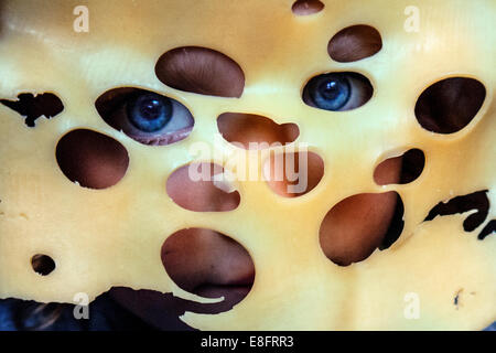 Mädchen schaut durch Löcher in einer Scheibe schweizer Käse Stockfoto