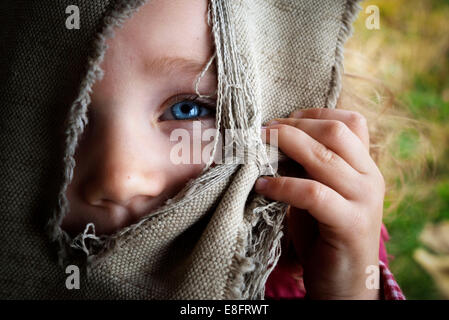Portrait eines Mädchens, das durch ein Loch in einem Vorhang schaut Stockfoto