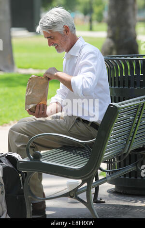 Geschäftsmann, sitzen auf der Bank im Park mit seinem Mittagessen Stockfoto