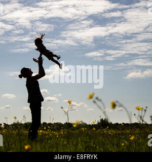 Silhouette der Mutter werfen Sohn in Luft Stockfoto