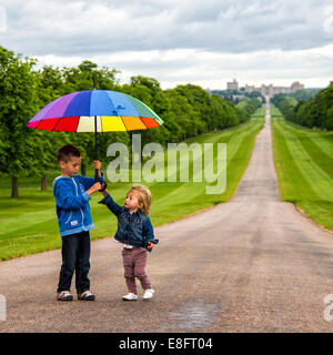 Junge und Mädchen spielen mit einem Regenschirm, Windsor Great Park, Berkshire, England, Großbritannien Stockfoto