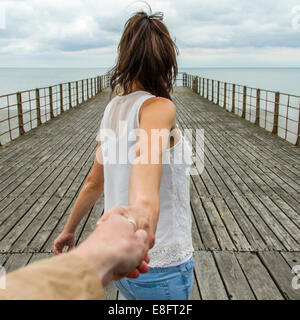 UK, Frau durchlöchern die Hand des Mannes auf pier Stockfoto