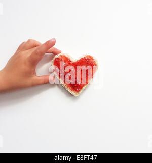 Junge Griff nach herzförmige Scheibe Brot und Marmelade Stockfoto