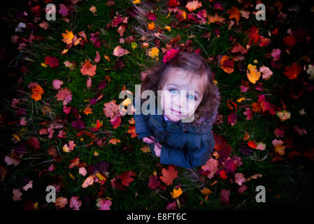 Ansicht von oben eines Mädchens, das zwischen Herbstblättern steht Stockfoto