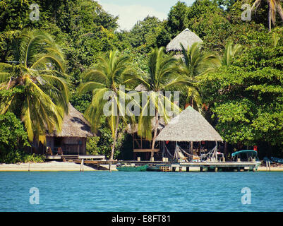 Eco Resort an einem karibischen Strand mit strohgedeckten Hütten und üppiger tropischer Vegetation, Bocas del Toro, Panama Stockfoto