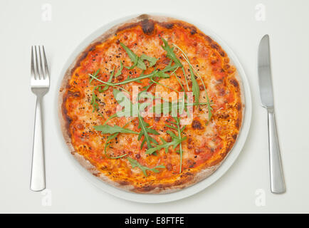 Blick von oben auf eine Pizza mit Käse und Tomaten mit Rucola auf einem Teller Stockfoto