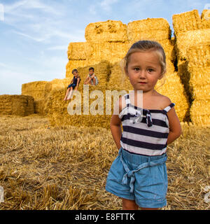 Drei Kinder spielen auf einem Feld von Heuballen, England, Großbritannien Stockfoto