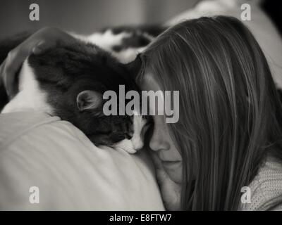 Mädchen auf einem Sofa sitzend, das ihre Katze nuzzelt, Schweden Stockfoto