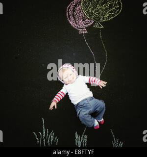 Lächelnder Baby Junge mit Kreidezeichnung von Ballons Stockfoto