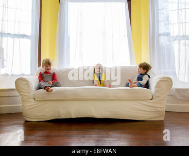 Drei Kinder sitzen auf einem Sofa im Wohnzimmer Stockfoto