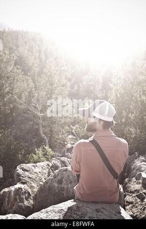 USA, Wyoming, Mann sitzt auf den Felsen über Bäume Stockfoto