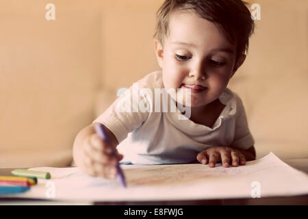 Junge sitzt am Tisch mit Buntstiften zeichnen Stockfoto