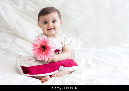 Lächelndes Mädchen, das eine Plastikblume hält Stockfoto