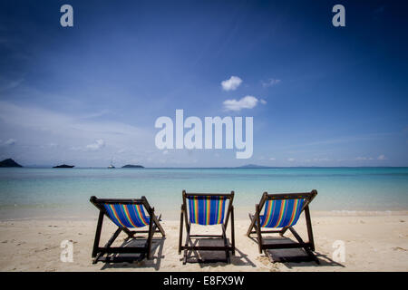 Drei Liegestühle in einer Reihe am Strand, Phuket, Thailand Stockfoto