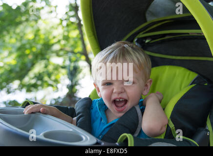 Junge sitzt in einem Kinderwagen, lachen Stockfoto