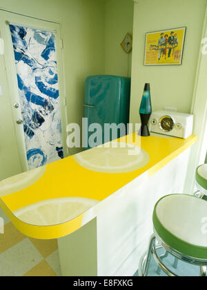 Lava-Lampe auf Zitrone gemusterte Arbeitsplatte im 50er Jahre Stil Küche mit blau gemusterten Rollo auf Glastür Stockfoto