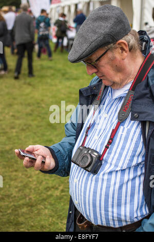 Rentner in eine flache Kappe mit Smartphone in England UK Stockfoto