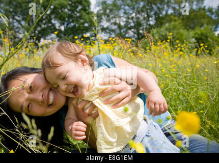 Beide lachen gemischt ethnische Zugehörigkeit (ostasiatische / caucasian) weiblichen Kleinkind durch ihr Koreanisch East Asian Mutter Natur statt, Stockfoto