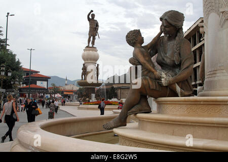 Fußgänger gehen vorbei an den Statuen und Brunnen in Karpos Aufstand Square in zentralen Skopje, Mazedonien Stockfoto