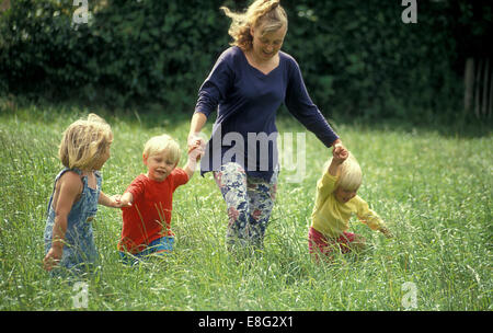 Frau läuft durch das Feld mit drei kleinen Kindern Stockfoto