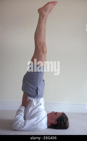 Mann tut Yoga zu Hause Schulterstand Stockfoto