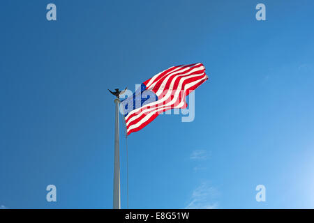 Die amerikanische Flagge flattern im Wind vor blauem Himmel mit Wolkenfetzen. Stockfoto