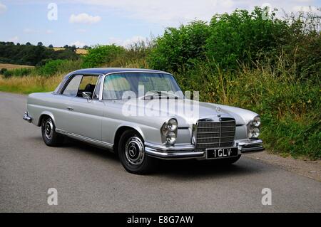 Mercedes-Benz 280SE Coupe stehend durch eine Hecke auf einer Landstrasse Stockfoto