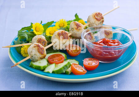 Fleischbällchen am Spieß, serviert mit frischem Salat und dekoriert mit gelben Blüten Stockfoto