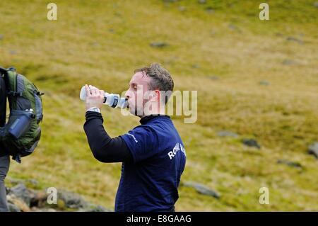 Fiel Läufer trinken aus einer Flasche Wasser auf einer Wanderung bis Scafell Pike im Lake District Stockfoto