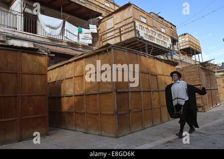 Jerusalem. 7. Oktober 2014. Ultra-orthodoxer Jude geht vorbei an einer Reihe von Sukkot, rituelle Stände während der jüdische Feiertag von Sukkot auf einem religiösen Viertel von Jerusalem am 7. Oktober 2014 verwendet. Religiöse Juden bauen temporäre Bauten für das einwöchige Festival zum Gedenken an den 40 Jahren des Reisens in der Wüste nach dem Auszug aus der Sklaverei in Ägypten. Donnerstag beginnt das diesjährige Sukkot. © Gil Cohen Magen/Xinhua/Alamy Live-Nachrichten Stockfoto