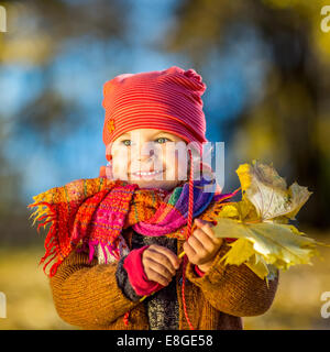 Kleine Mädchen spielen mit Herbstlaub Stockfoto