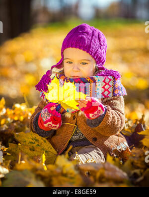 Kleine Mädchen spielen mit Herbstlaub Stockfoto